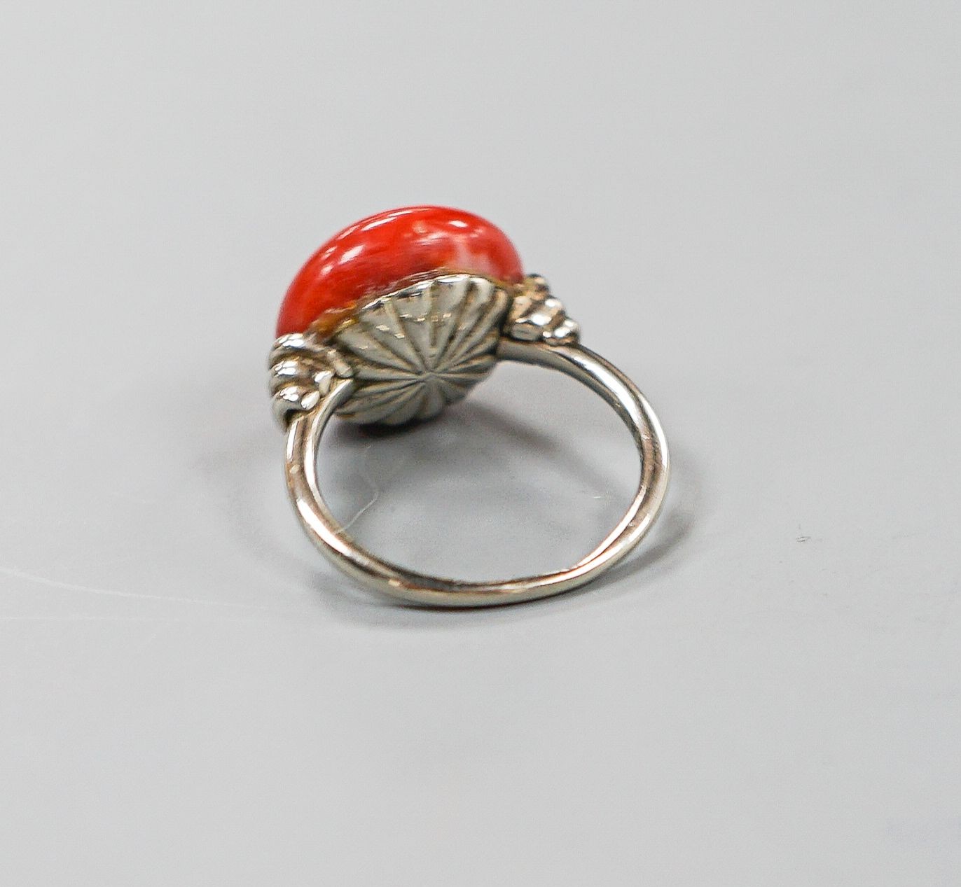 A 585 white metal and stained? cabochon coral set dress ring, size I, gross weight 5.5 grams.